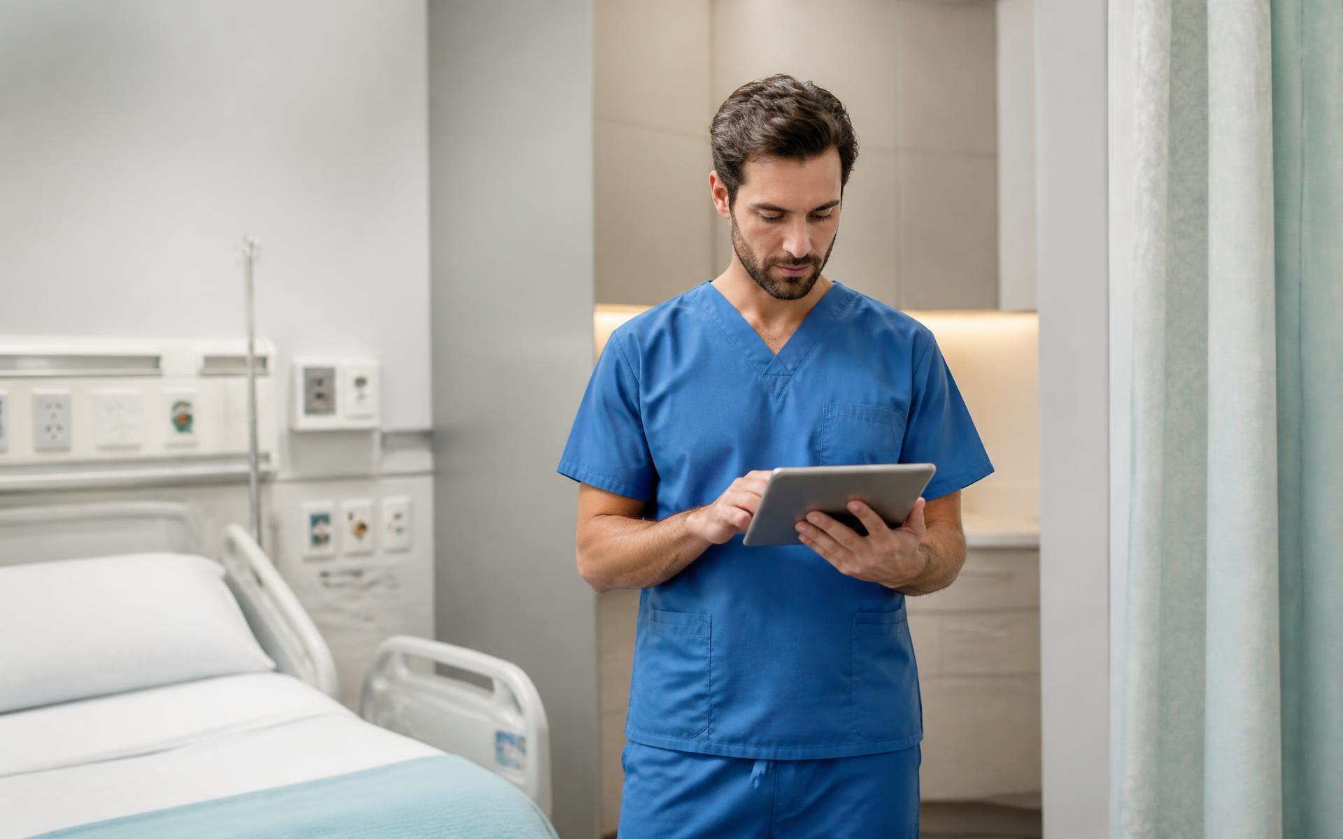 Enfermeiro usa scrub azul em ambiente hospitalar com fundo suavemente desfocado.