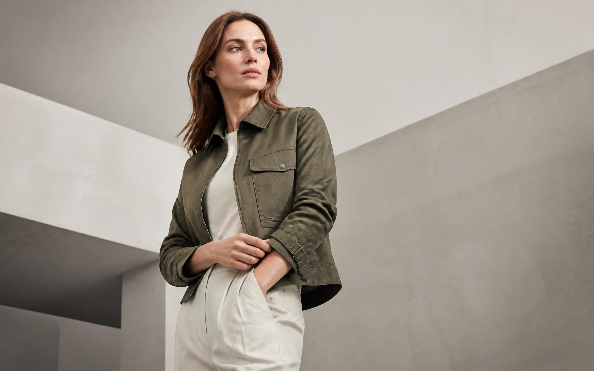 Modelo veste jaqueta contemporânea de sarja cáqui em estúdio cinza e branco.
